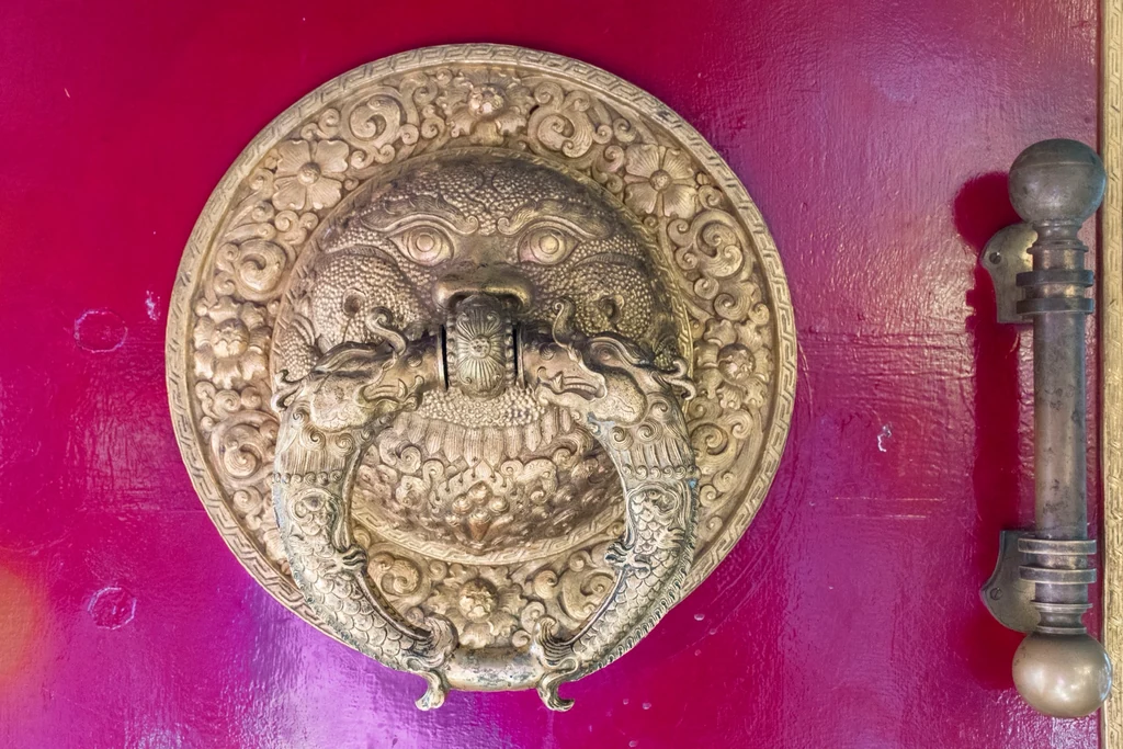 Koyu pembe bir kapıya monte edilmiş, aslan başı biçiminde işlemeli pirinç kapı tokmağı.